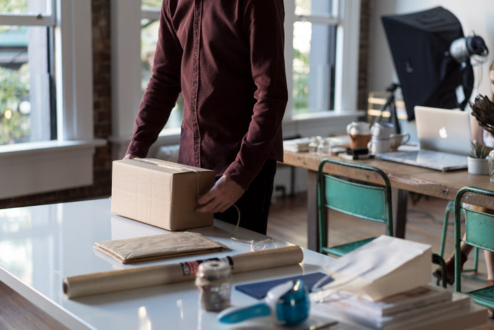 A person packing an e-commerce package wondering if they should sell CBD on Amazon